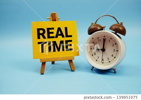 Real Time text with alarm clock on blue background Real Time text with alarm clock on blue background 139951075