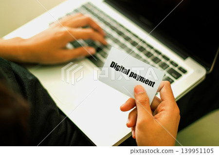 Digital payment' card held while using a laptop for online transactions. Digital payment' card held while using a laptop for online transactions. 139951105