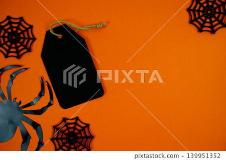 Spooky orange background featuring a black gift tag, spider webs, and a creepy spider for Halloween-themed labels, party invites, or seasonal promotions. 139951352