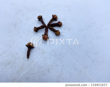 dried whole cloves (Syzygium aromaticum) arranged in a radial pattern on a clean, light-colored surface. dried whole cloves (Syzygium aromaticum) arranged in a radial pattern on a clean, light-colored surface. 139951657
