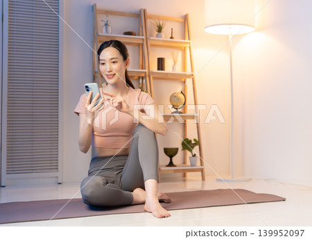 A woman in yoga wear looking at her smartphone at night. A woman in yoga wear looking at her smartphone at night. 139952097
