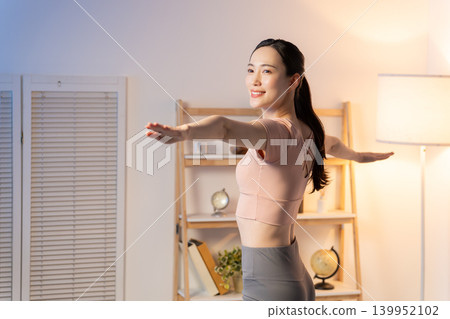 一位女士晚上在家做瑜伽 139952102