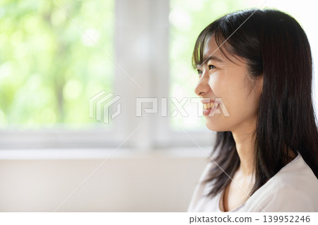 A young Japanese woman smiles and chats while operating a computer. A young Japanese woman smiles and chats while operating a computer. 139952246