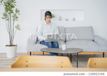 一位女士在家工作,一邊看著電腦。 一位女士在家工作,一邊看著電腦。 139952348