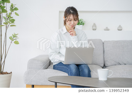 一位女士在家工作,一邊看著電腦。 一位女士在家工作,一邊看著電腦。 139952349