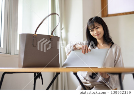 A young Japanese woman takes her laptop out of her bag and prepares to work. A young Japanese woman takes her laptop out of her bag and prepares to work. 139952359