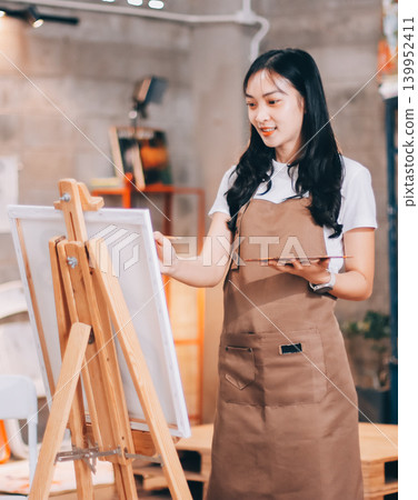 Female artist wears black hat posing near picture indoor the studio Female artist wears black hat posing near picture indoor the studio 139952411