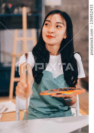 Female artist wears black hat posing near picture indoor the studio Female artist wears black hat posing near picture indoor the studio 139952435