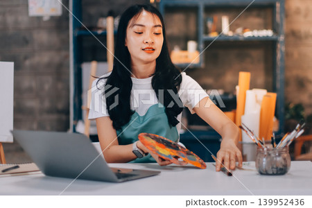 Female artist wears black hat posing near picture indoor the studio Female artist wears black hat posing near picture indoor the studio 139952436