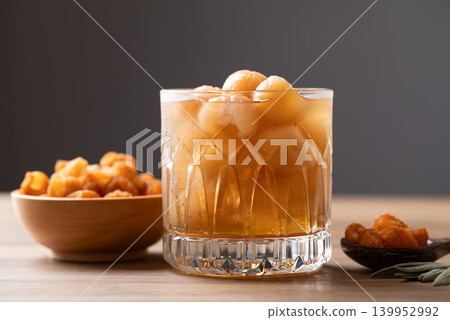 Iced longan juice in glass with dried longan fruit on wooden background Iced longan juice in glass with dried longan fruit on wooden background 139952992
