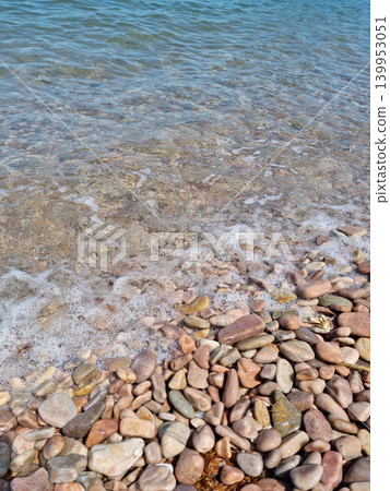 It is a beach with round pebbles. 139953051