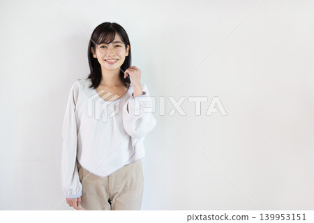 一位年輕的日本女子在白色背景前對著鏡頭微笑。 139953151