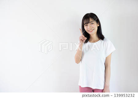 一位年輕的日本女子對著鏡頭微笑，在白色背景前舉起食指。 139953232