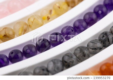 Amethyst gemstone bead strands close up on white tray Amethyst gemstone bead strands close up on white tray 139953270