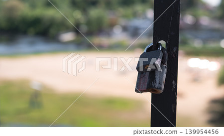 Lonely Padlock On Railing Overlooking Beach, Traveler Keepsake Left As Quiet Symbol Of Security Soft Bokeh, Sunlit Shore, Gentle Breeze Suggested By Rippled Water, Peaceful Summer Mood Lonely Padlock On Railing Overlooking Beach, Traveler Keepsake Left As Quiet Symbol Of Security Soft Bokeh, Sunlit Shore, Gentle Breeze Suggested By Rippled Water, Peaceful Summer Mood 139954456