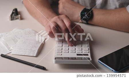 Wide View Hands Reconciling Receipts With Calculator, Phone And Pencil On Desk, Organized Stacks Of Invoices And Notes, Smartwatch Visible, Methodical Tallying Of Monthly Totals And Financial Records 139954571