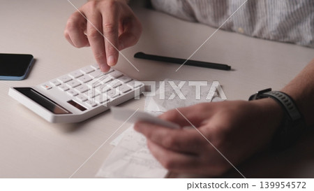Closeup Hands Pressing Calculator Keys, Crumpled Receipts Scattered On Desk, Pencil And Phone Beside, Wristwatch Visible, Freelancer Tracking Expenses And Totals With Focused Tension 139954572