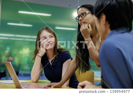 A young business team in their 20s having a meeting in a casual office setting. A young business team in their 20s having a meeting in a casual office setting. 139954977