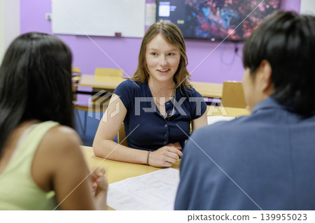 A young man and woman discuss a drawing, showcasing teamwork and learning. A young man and woman discuss a drawing, showcasing teamwork and learning. 139955023