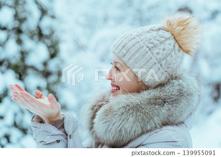 Young happy woman in warm winter clothing catching snowflakes Young happy woman in warm winter clothing catching snowflakes 139955091