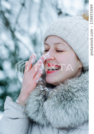 Portrait of young happy woman in warm winter clothing with snow on nose Portrait of young happy woman in warm winter clothing with snow on nose 139955094