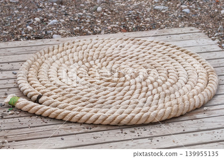Folded vintage sea rope lies on seashore. Marina seascape. Folded vintage sea rope lies on seashore. Marina seascape. 139955135