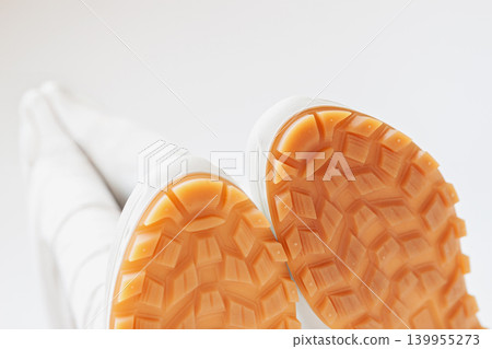 Bottom view of demi season boots with orange rubber sole and tread pattern shown close up, white background. Rain boots protection, waterproof footwear, grip, traction, autumn weather, product mockup Bottom view of demi season boots with orange rubber sole and tread pattern shown close up, white background. Rain boots protection, waterproof footwear, grip, traction, autumn weather, product mockup 139955273