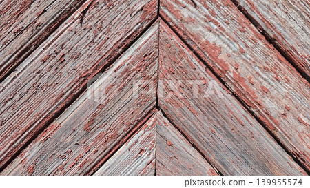 Old weathered wooden planks with peeling red paint arranged in a diagonal chevron pattern, concept of vintage rustic texture and architectural decay Old weathered wooden planks with peeling red paint arranged in a diagonal chevron pattern, concept of vintage rustic texture and architectural decay 139955574