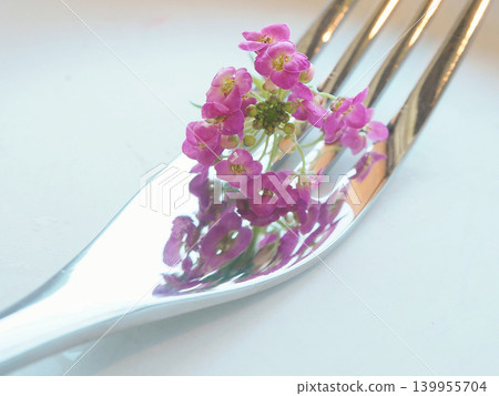 盤子上放著一把叉子和幾朵紫色的花。 139955704