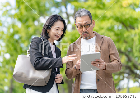 兩個人一邊看著平板電腦一邊交談 商業 兩個人一邊看著平板電腦一邊交談 商業 139955783