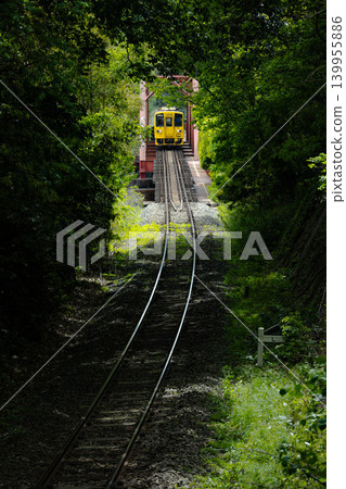 一列當地列車駛過一座鐵路橋,橋下是一片綠樹成蔭的隧道。 一列當地列車駛過一座鐵路橋,橋下是一片綠樹成蔭的隧道。 139955886
