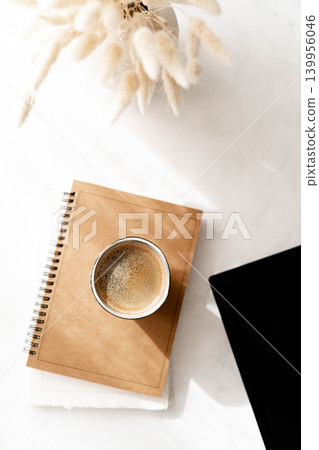 Minimal flat lay with coffee cup, notebook and laptop corner on a white surface 139956046
