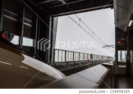 Infrastructure in heavy snowfall areas: A winter scene featuring a Shinkansen station platform designed for cold climates and a train waiting to depart. Infrastructure in heavy snowfall areas: A winter scene featuring a Shinkansen station platform designed for cold climates and a train waiting to depart. 139956163