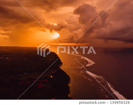 Aerial sunset or sunrise view of tropical cliffs and coastline with glowing storm clouds 139956326