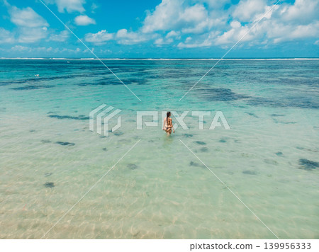 Woman standing in crystal clear water in tropical ocean lagoon Woman standing in crystal clear water in tropical ocean lagoon 139956333
