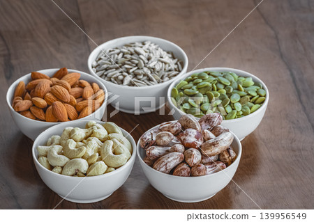 Nuts of different varieties on a wooden table. Pumpkin seeds, sunflower seeds, cashews, almonds Nuts of different varieties on a wooden table. Pumpkin seeds, sunflower seeds, cashews, almonds 139956549
