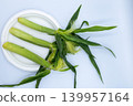 A horizontal cut of three fresh, unhulled baby corn cobs arranged on a white plate with copy space on the right. 139957164