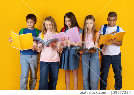 Five diverse schoolchildren standing with backpacks reading colorful open books Five diverse schoolchildren standing with backpacks reading colorful open books 139957284