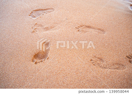 Human footprints remain on sandy beach near the shoreline during summer seaside vacation weather. Beach resort lifestyle travel memories and coastal tourism Human footprints remain on sandy beach near the shoreline during summer seaside vacation weather. Beach resort lifestyle travel memories and coastal tourism 139958044