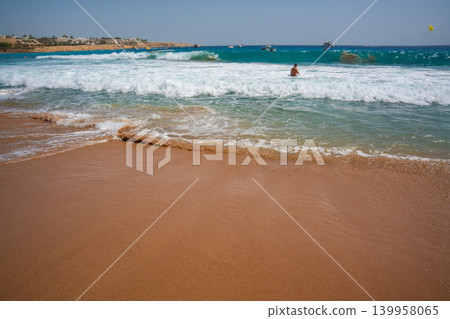 Caucasian man swims in sea waves on a sandy beach in Sharm El Sheikh Egypt with turquoise Red Sea water boats and coastal resort view. Beach resort lifestyle and summer tourism on the Red Sea Caucasian man swims in sea waves on a sandy beach in Sharm El Sheikh Egypt with turquoise Red Sea water boats and coastal resort view. Beach resort lifestyle and summer tourism on the Red Sea 139958065