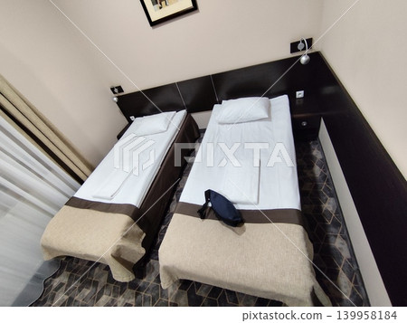 Simple standard hotel room interior featuring two single twin beds 139958184