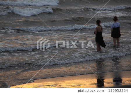 A traveler bathed in the setting sun at the water's edge A traveler bathed in the setting sun at the water's edge 139958264