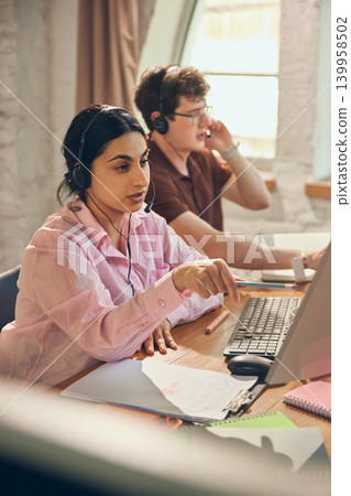 Female support operator pointing at screen during client call. Female support operator pointing at screen during client call. 139958502