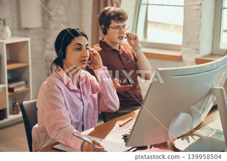 Call center agents handling client calls at computer workstations. Call center agents handling client calls at computer workstations. 139958504