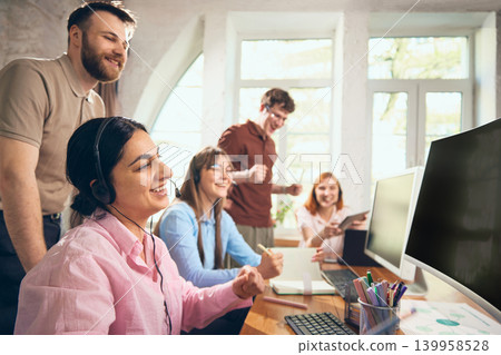 Happy customer support team celebrating successful result in office. Happy customer support team celebrating successful result in office. 139958528