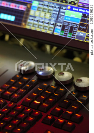 Close-up of a professional lighting control console with illuminated buttons and blurred digital display. Close-up of a professional lighting control console with illuminated buttons and blurred digital display. 139959082
