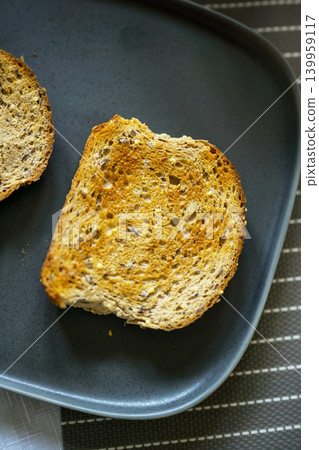 Whole grain seeded toast slices on dark plate, healthy breakfast food concept Whole grain seeded toast slices on dark plate, healthy breakfast food concept 139959117