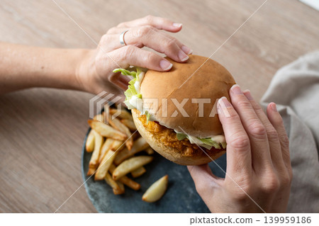 Woman holding crispy chicken burger Woman holding crispy chicken burger 139959186