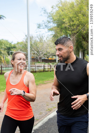 Happy couple jogging together in park and talking during outdoor workout 139959249