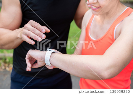 Female runner checking smartwatch during outdoor workout with training partner 139959250